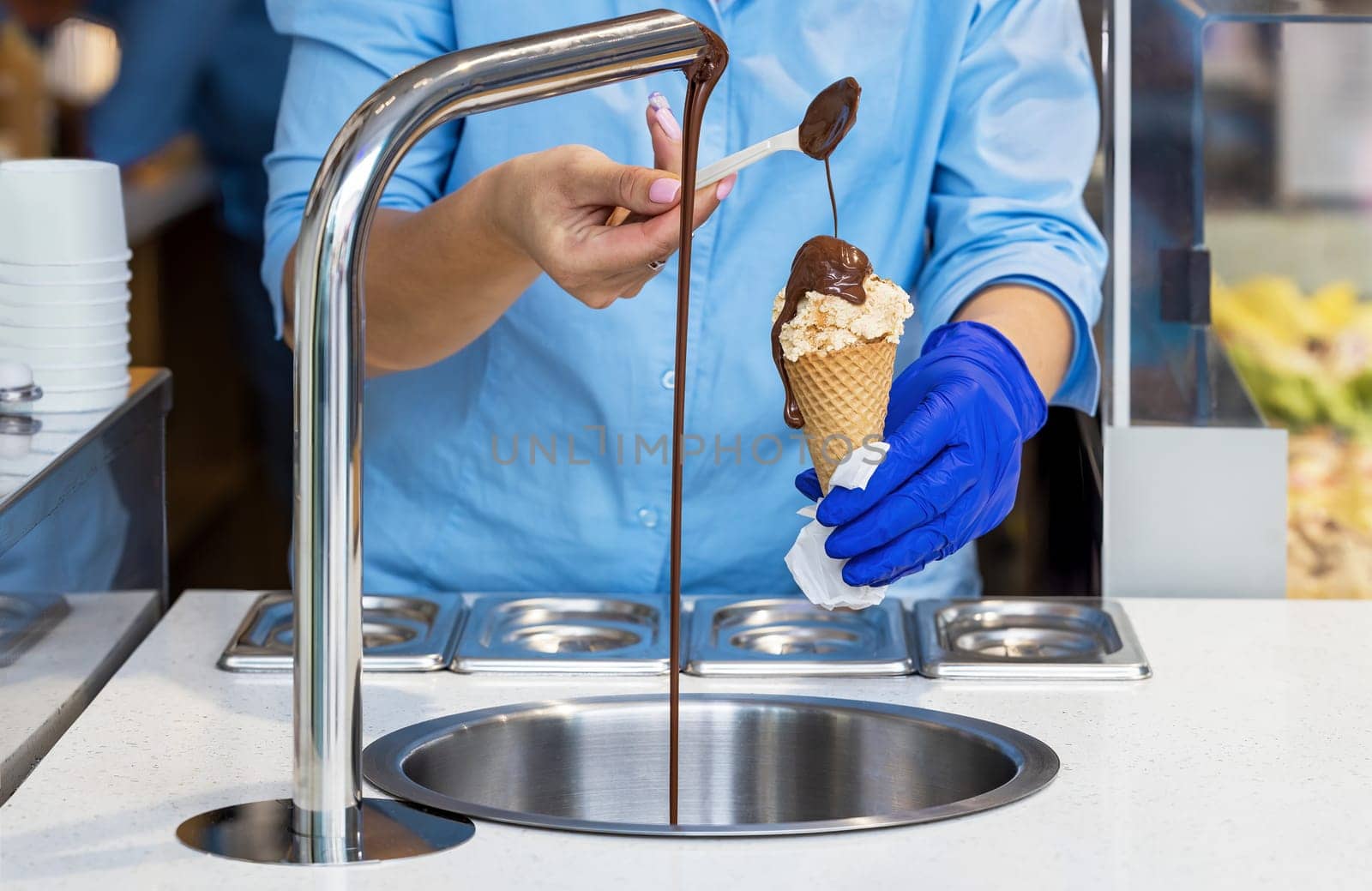 Saleswoman in a confectionery arranging chocolate on vanilla ice cream with a teaspoon