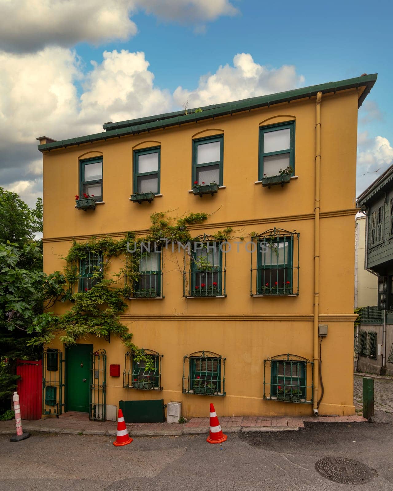 Facade of residential building with walls painted in orange and green, with wrought iron window and climber plants, at an alley suited in Kuzguncuk neighborhood, Uskudar district, Istanbul, Turkey