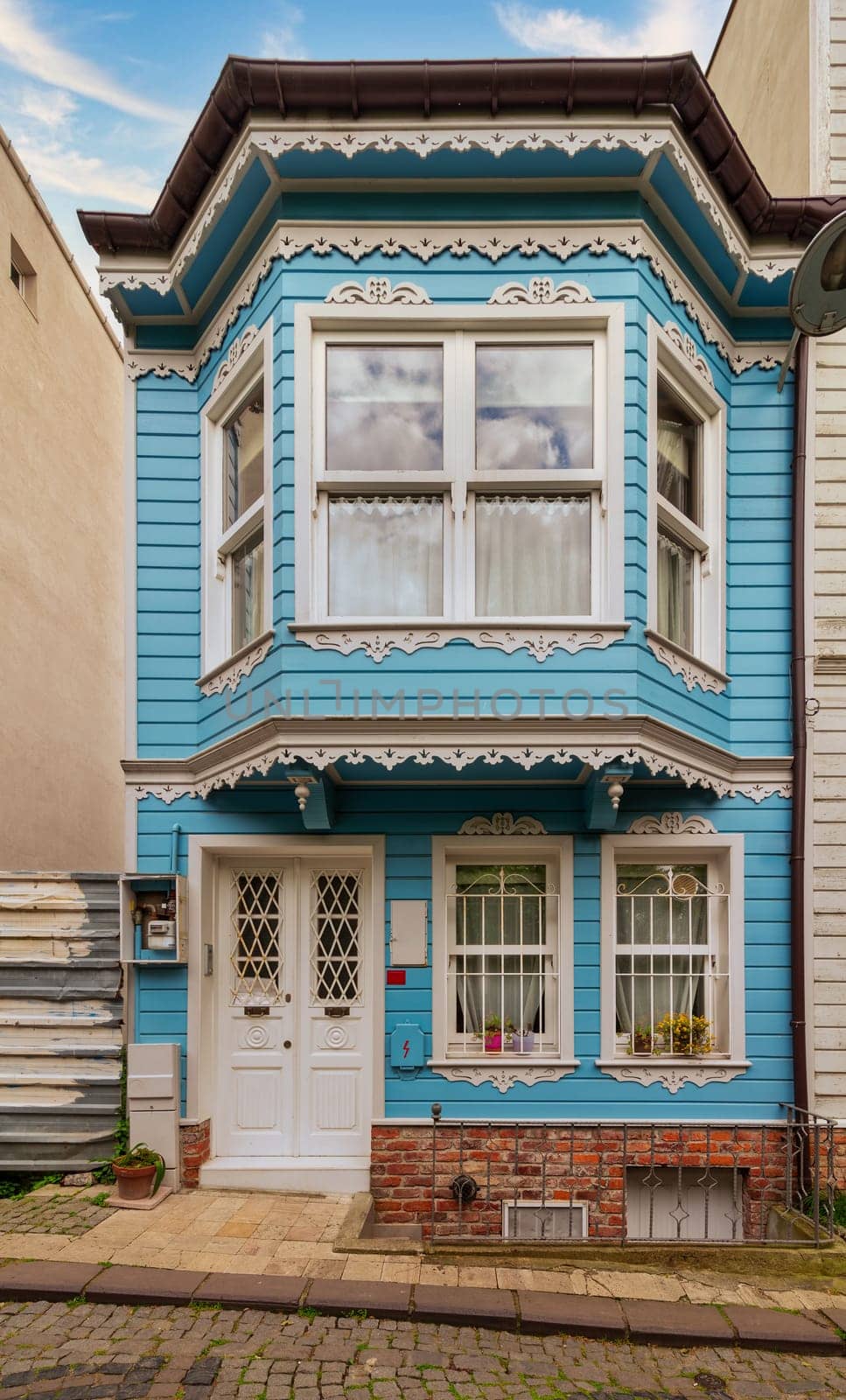 Facade of colorful wooden residential building painted in blue and white, with wrought iron window, at an alley suited in Kuzguncuk neighborhood, Uskudar district, Istanbul, Turkey