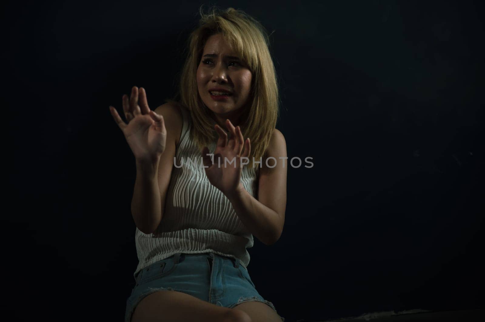 Crying woman raised her hands for dissuade, Abuse, campaign stop violence against women while sitting in abandoned room. Stop violence, sexual harassment and rape concept.