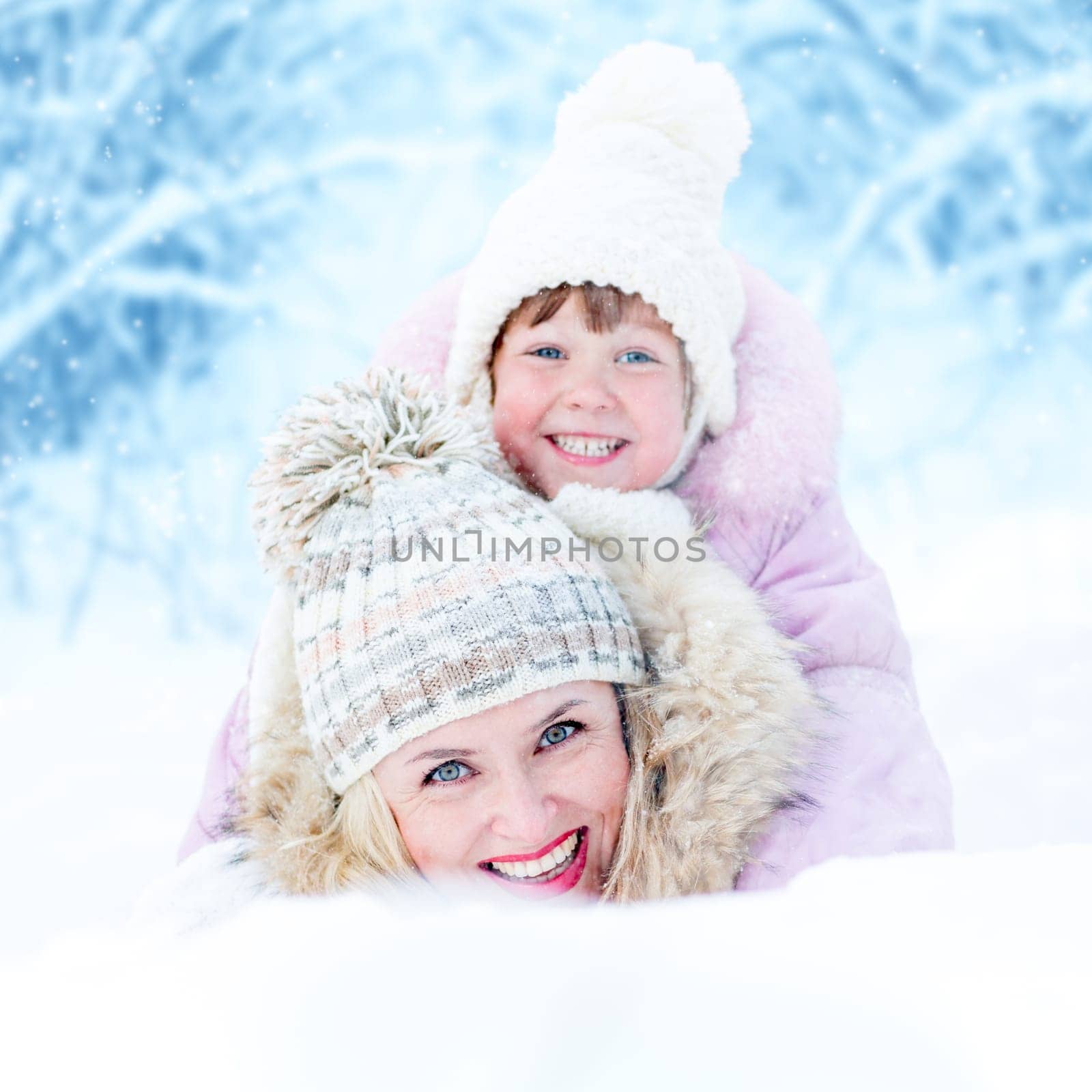 Happy mother and kid lying in snowdrift