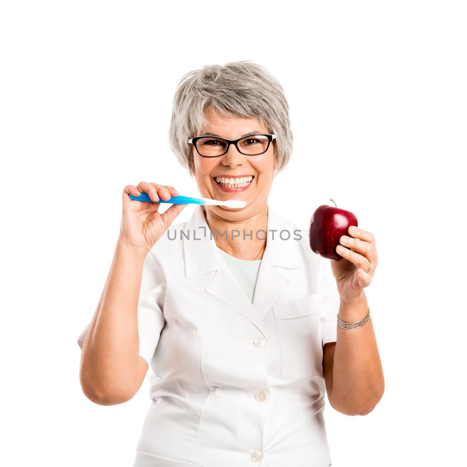 Elderly woman brushing her teeth and holding a red apple
