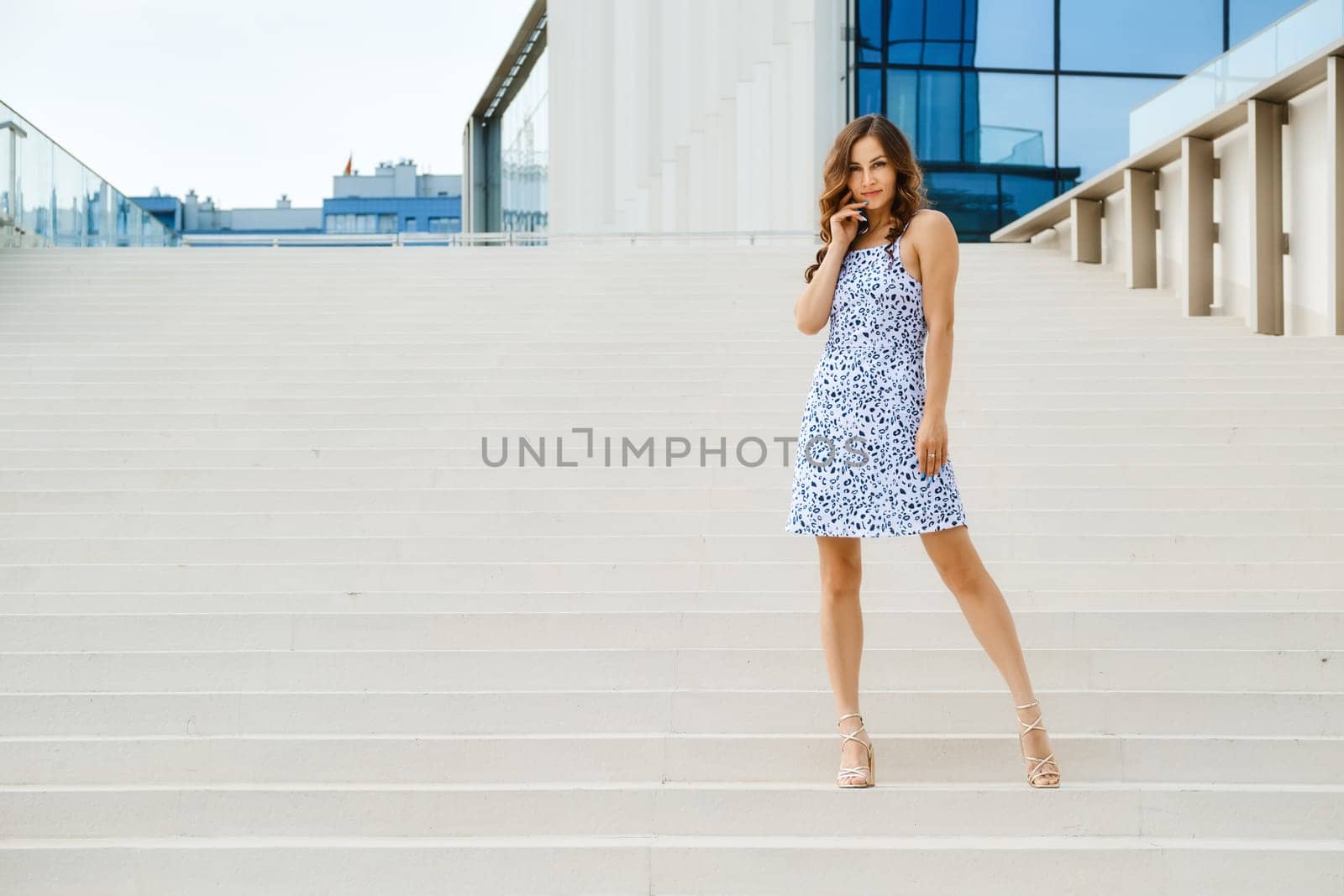 Trendy woman in patterned summer sundress standing on stairs
