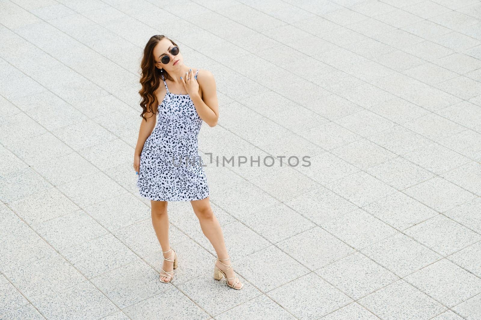 Top view of caucasian woman in stylish patterned sundress and sunglasses