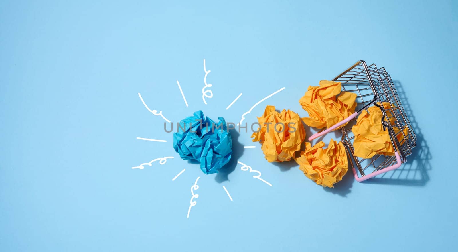 Crumpled paper balls on a blue background and a shopping basket. Concept of a new idea