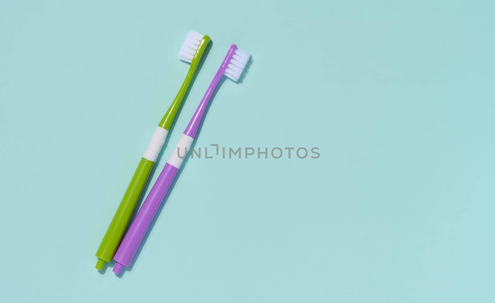 Two plastic toothbrushes on a blue background, oral hygiene.