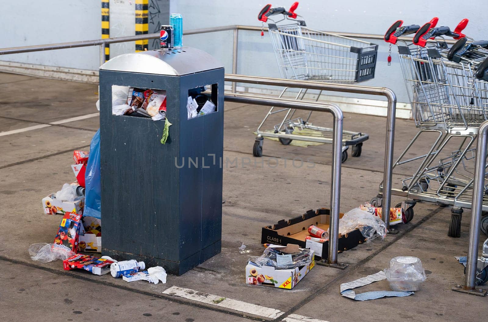 Overflowing dumpster, trash can with plastic bags and cardboard, filthy shopping center, Alleencenter in Trier, Germany
