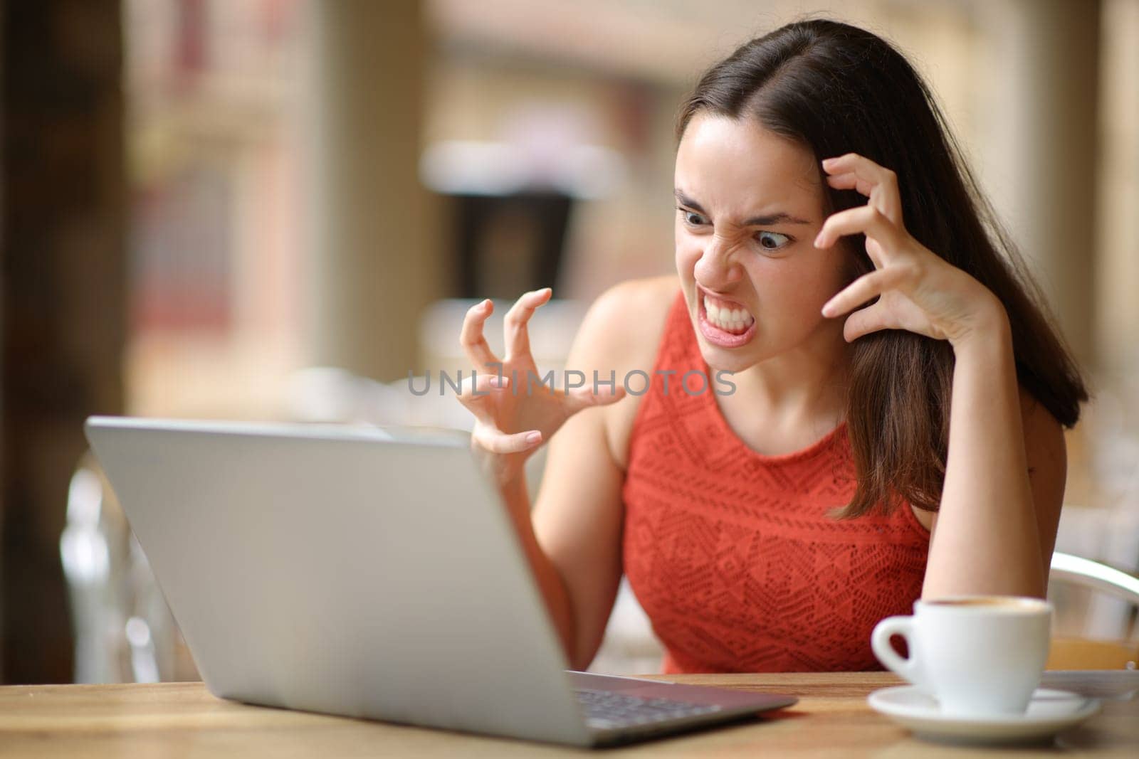 Angry woman having problems with a laptop in a bar terrace