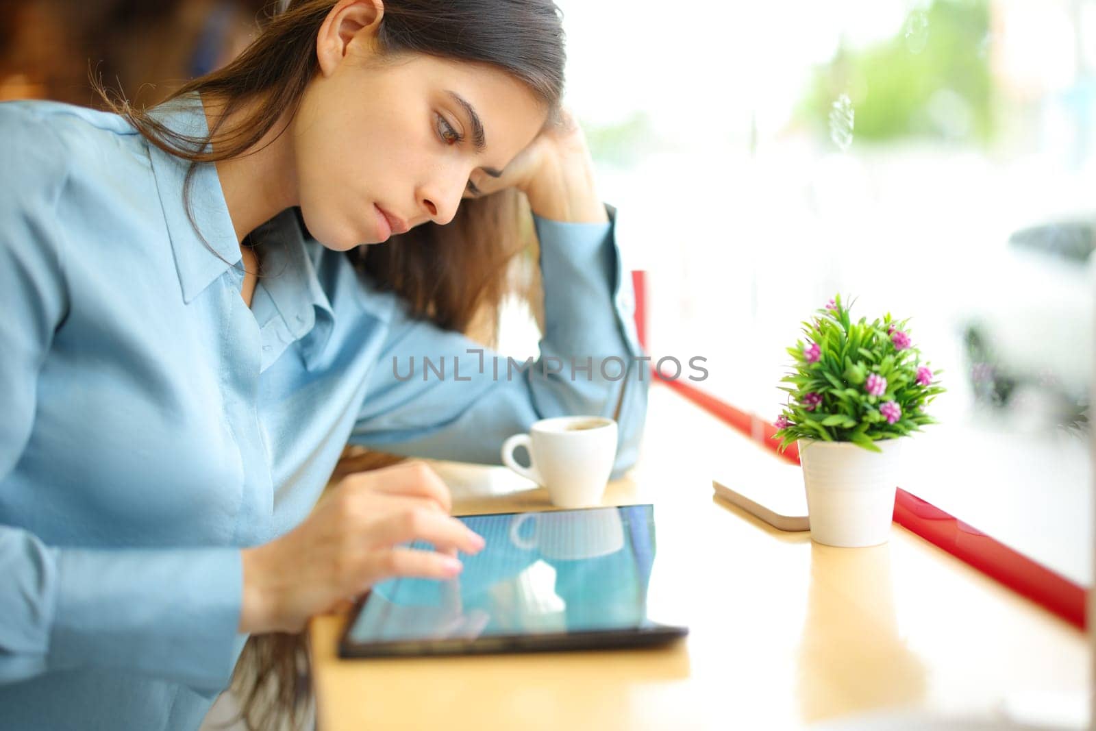 Serious woman using tablet sitting in a coffee shop