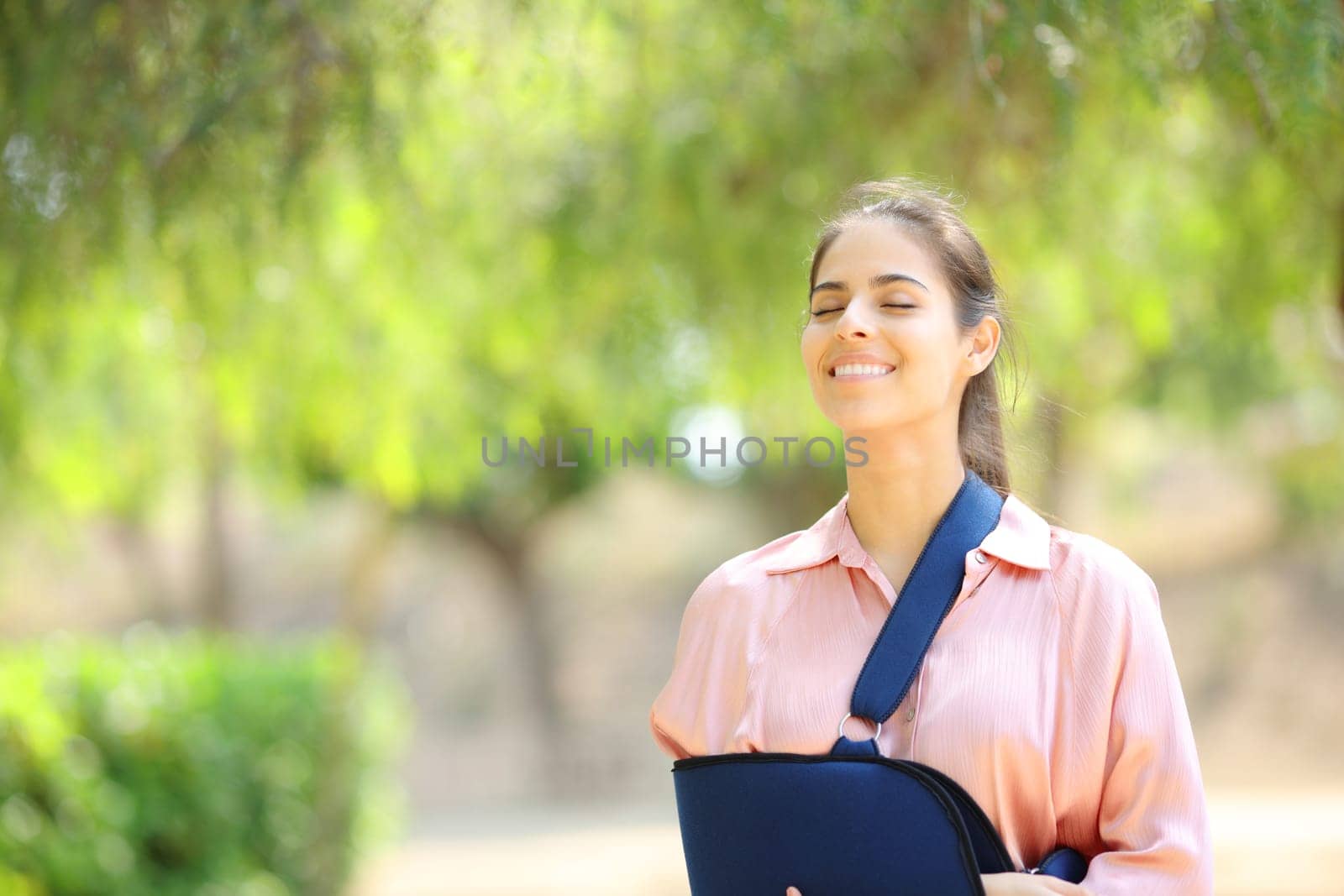 Happy convalescent woman breathing fresh air in a green park