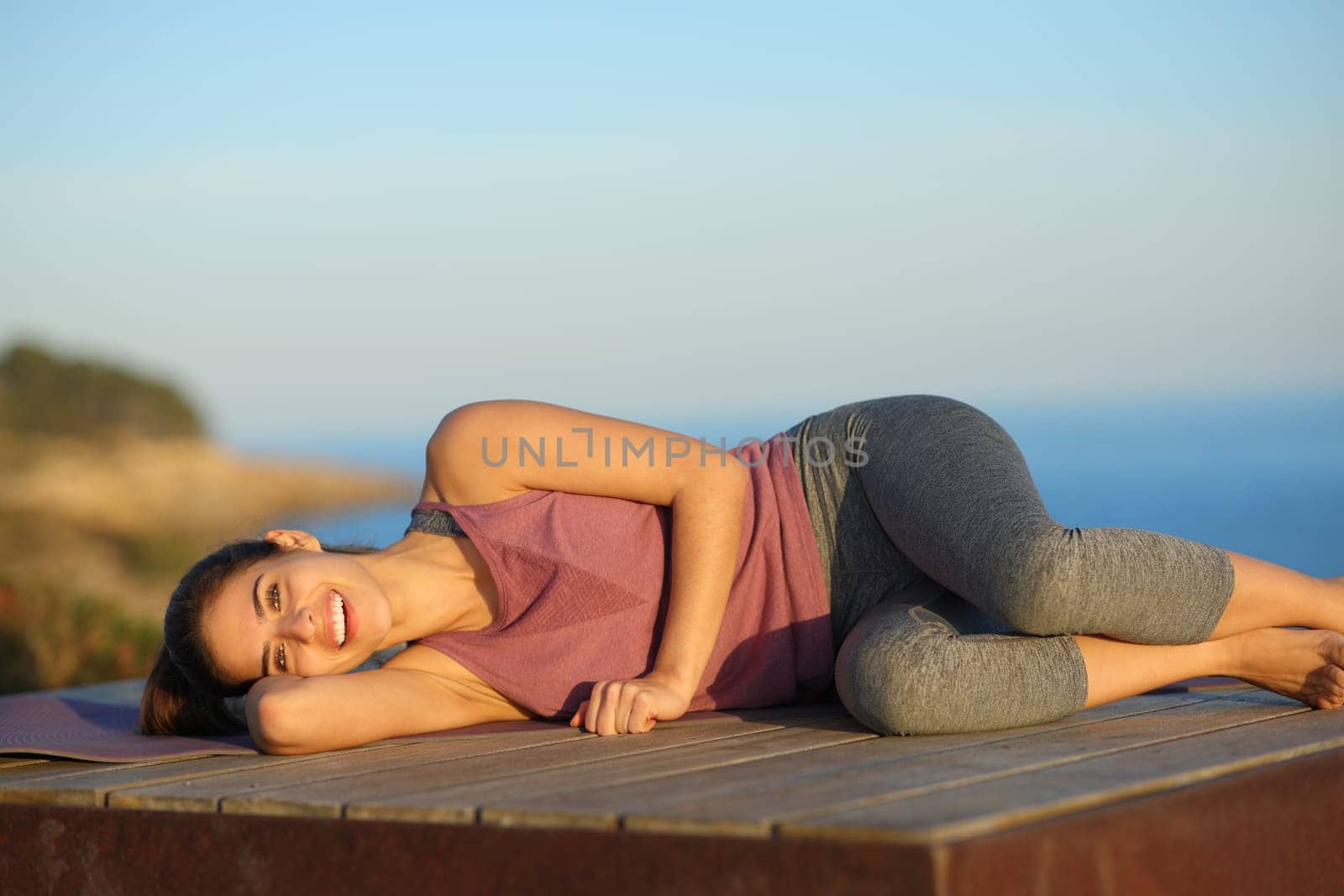 Happy yogi resting in a wooden platform laughing on the beach