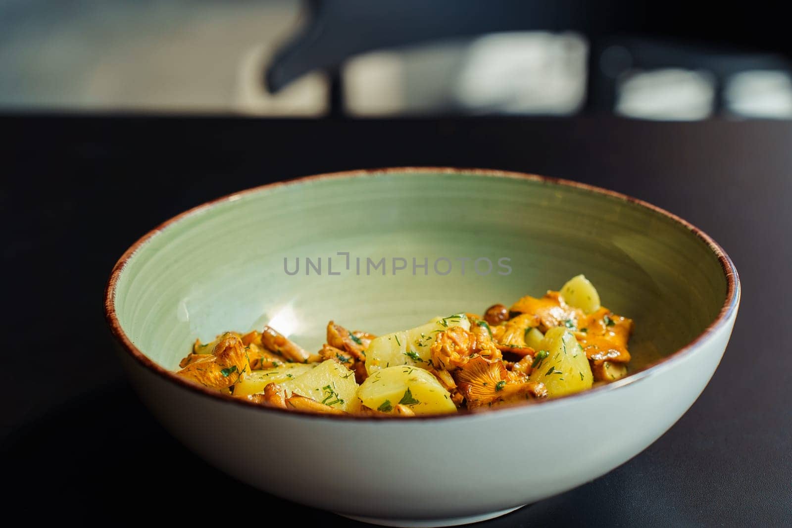 Fresh summer lunch made with vegetarian local produce. Wild chanterelle mushrooms with boiled potatoes and herbs in a bowl on the table.