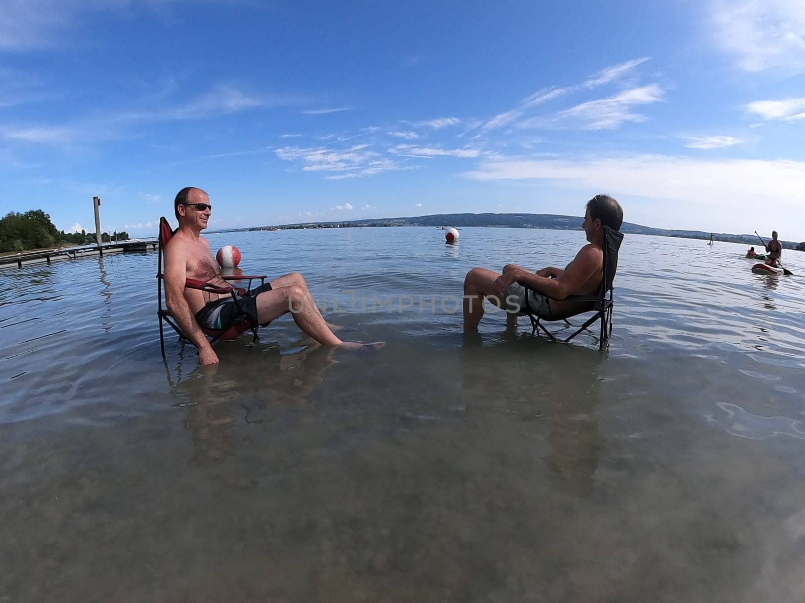Theme picture Summer - Summer day at Lake Constance  This is how it can be endured: Despite the summer heat,these two men have positioned their sitting chair right in Lake Constance and thus find the right cooling not only for their feet.  Young and old sought to cool off on a boat trip,an excursion with the Stand Up Paddle (SUP) or while swimming. The next few days are expected to remain hot in summer if thunderstorms are likely to occur
