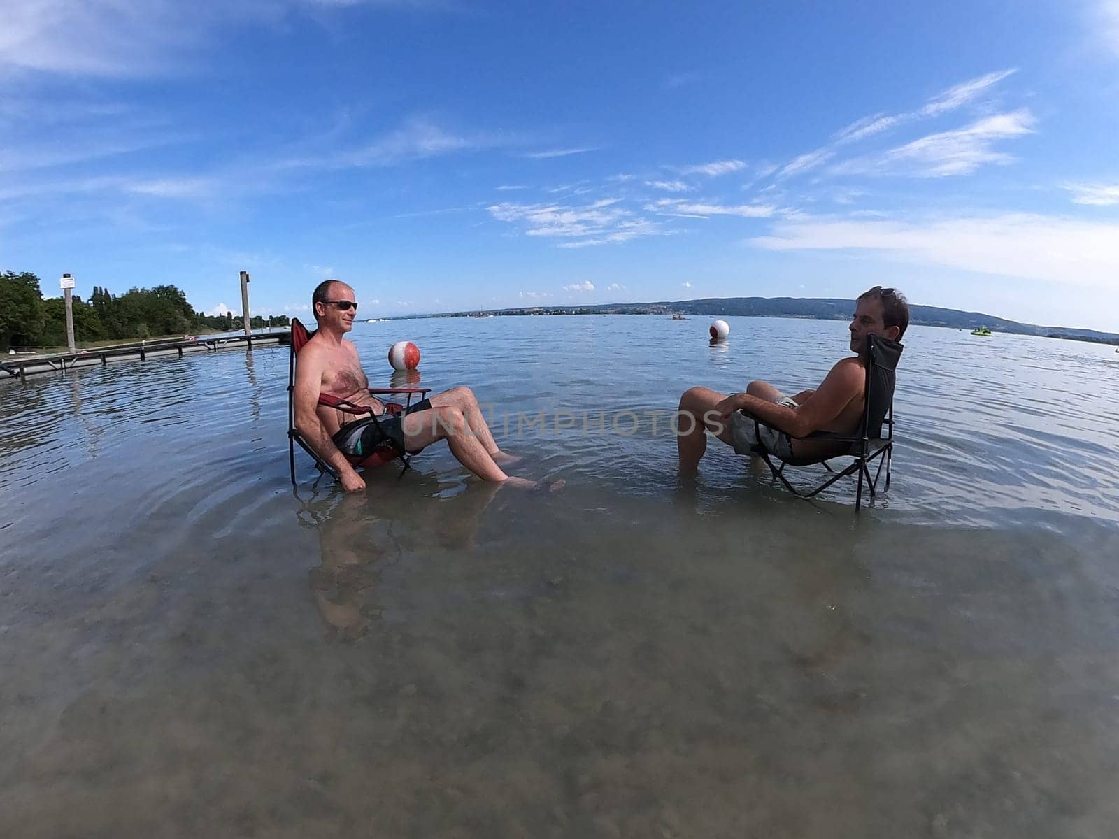Theme picture Summer - Summer day at Lake Constance  This is how it can be endured: Despite the summer heat,these two men have positioned their sitting chair right in Lake Constance and thus find the right cooling not only for their feet.  Young and old sought to cool off on a boat trip,an excursion with the Stand Up Paddle (SUP) or while swimming. The next few days are expected to remain hot in summer if thunderstorms are likely to occur