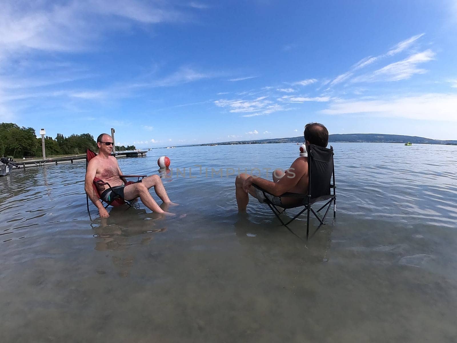 Theme picture Summer - Summer day at Lake Constance  This is how it can be endured: Despite the summer heat,these two men have positioned their sitting chair right in Lake Constance and thus find the right cooling not only for their feet.  Young and old sought to cool off on a boat trip,an excursion with the Stand Up Paddle (SUP) or while swimming. The next few days are expected to remain hot in summer if thunderstorms are likely to occur