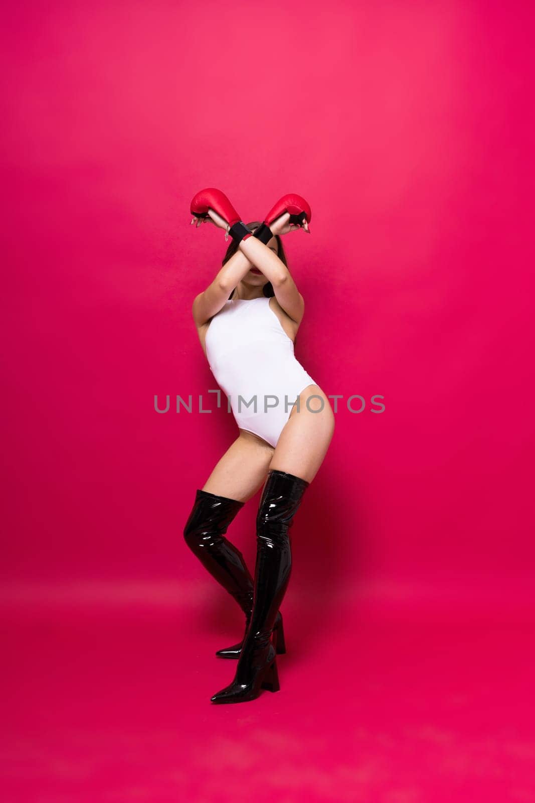Studio portrait of female seductive boxer in bodysuit and gloves