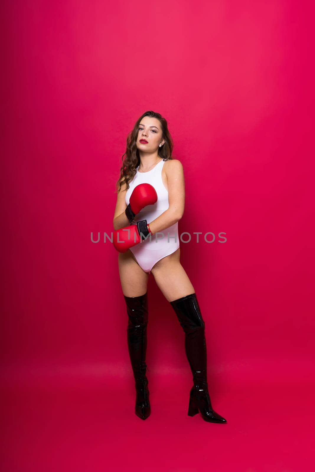Studio portrait of female seductive boxer in bodysuit and gloves