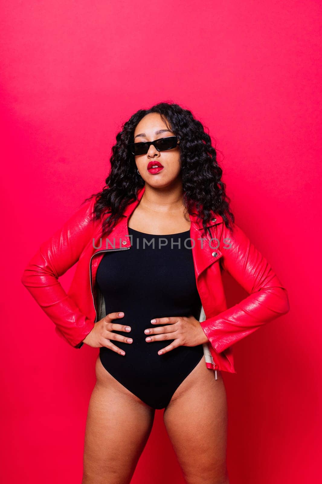 Seductive african woman posing in a black bodysuit and jacket in studio. Fit sporty female.