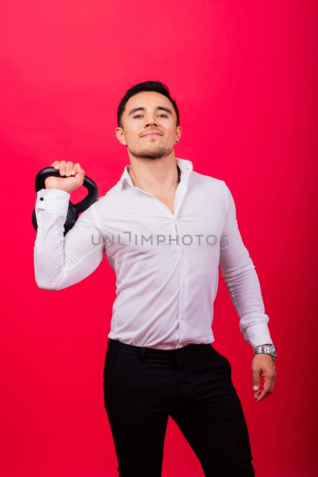 Attractive businessman Exercising With Kettlebell In a studio, red background