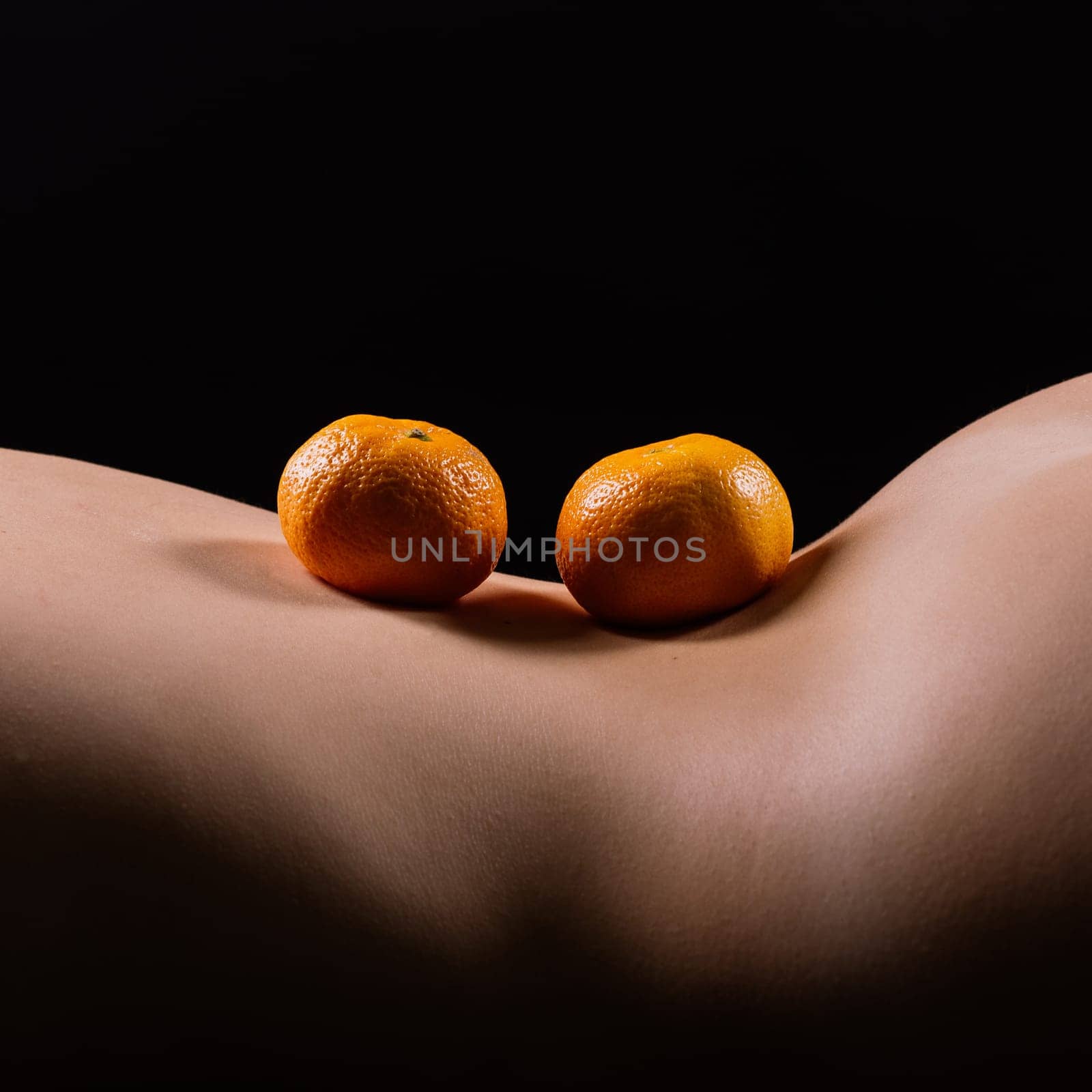 Oranges, tangerines - citrus on woman's body. Naked woman lying on her back with fruit located