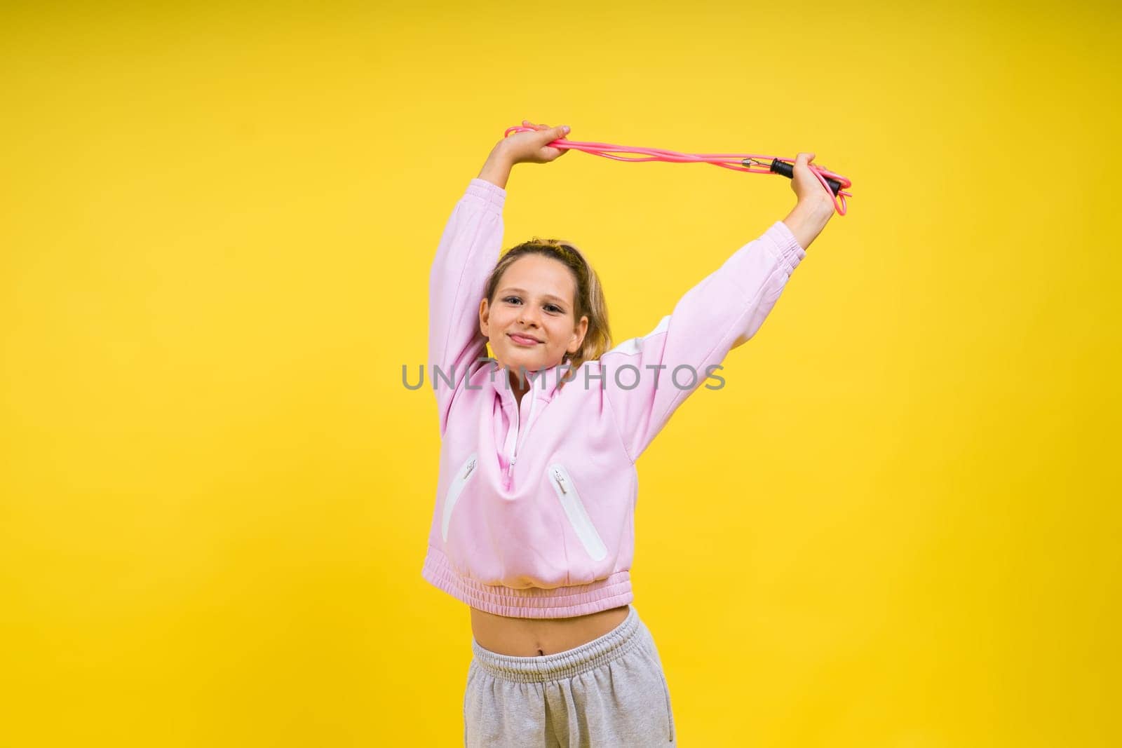 Beautiful sportsgirl with skipping rope isolated on a yellow studio
