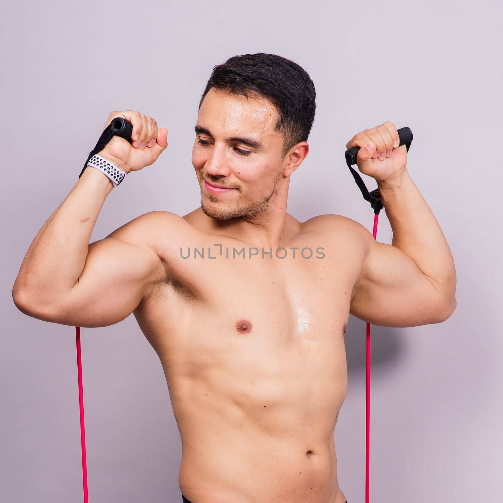 Fit young athlete preparing for a bicep muscle arms exercise. Isolated over grey studio background.