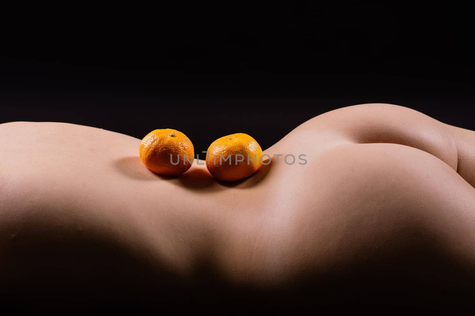 Oranges, tangerines - citrus on woman's body. Naked woman lying on her back with fruit located
