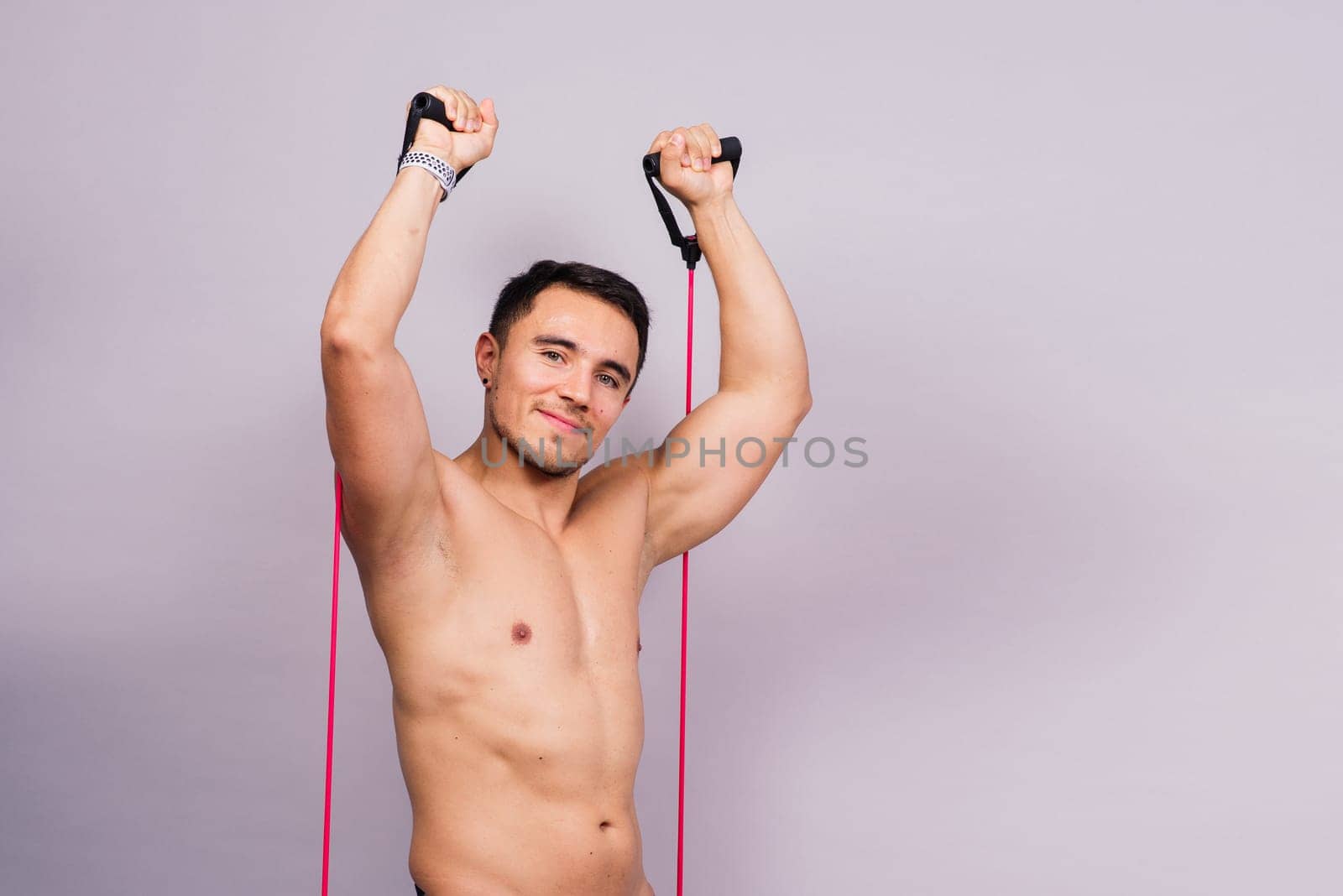 Fit young athlete preparing for a bicep muscle arms exercise. Isolated over grey studio background.