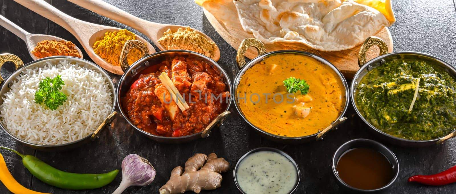 Composition with indian dishes: madras paneer, palak paneer and shahi paneer with basmati rice served in original indian karahi pots.