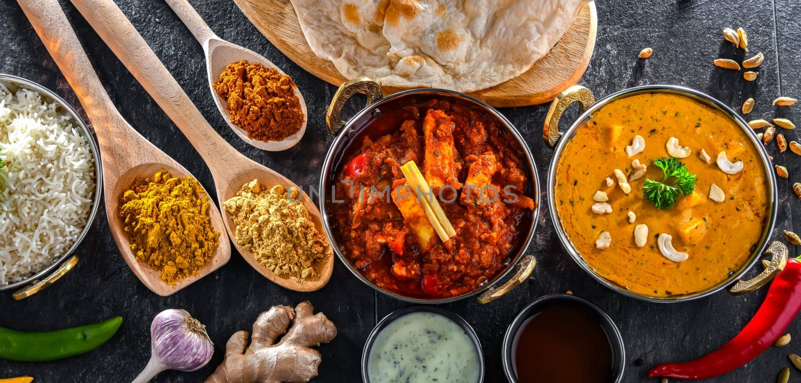 Composition with indian dishes: madras paneer, palak paneer and shahi paneer with basmati rice served in original indian karahi pots.
