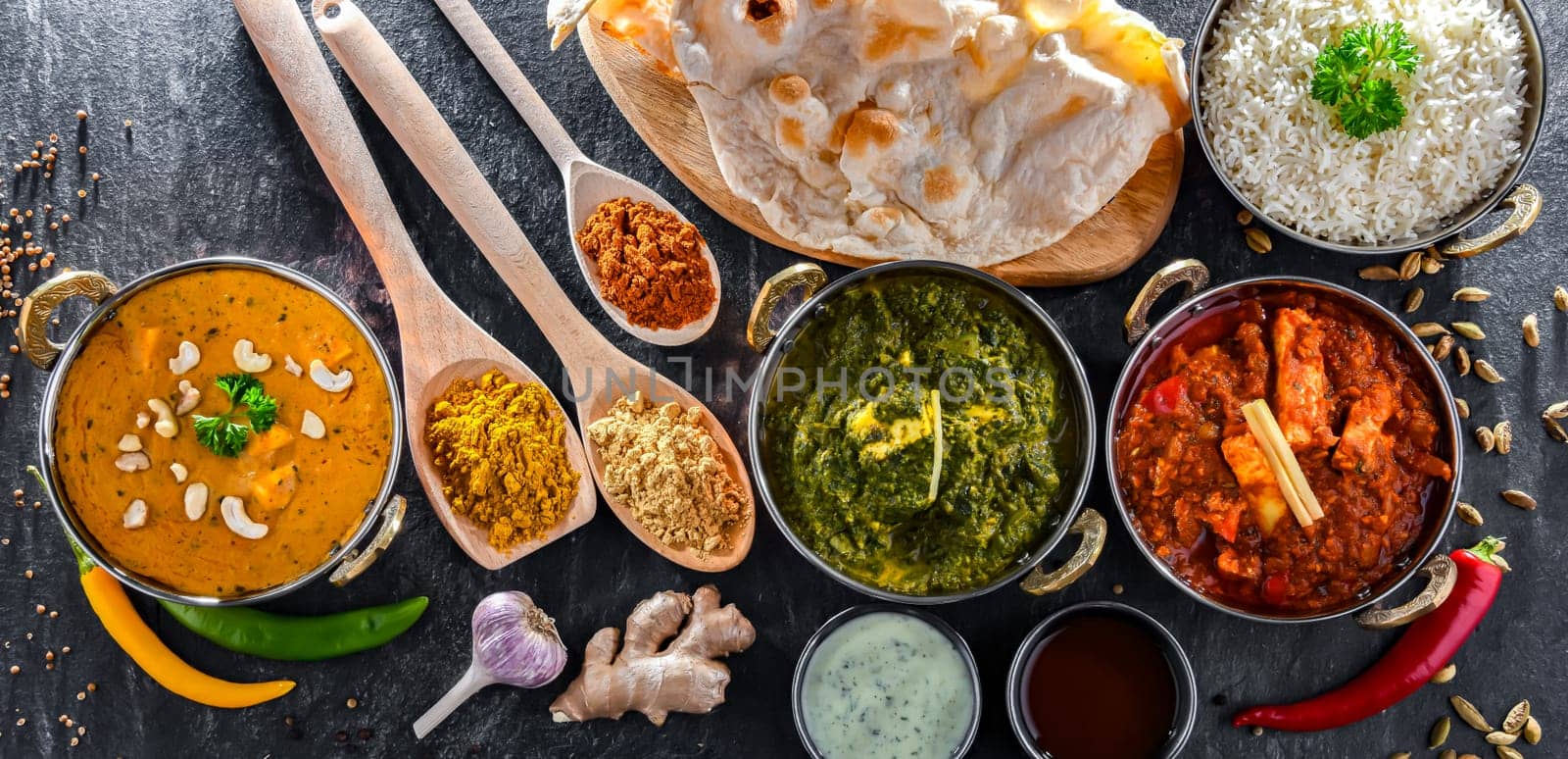 Composition with indian dishes: madras paneer, palak paneer and shahi paneer with basmati rice served in original indian karahi pots.