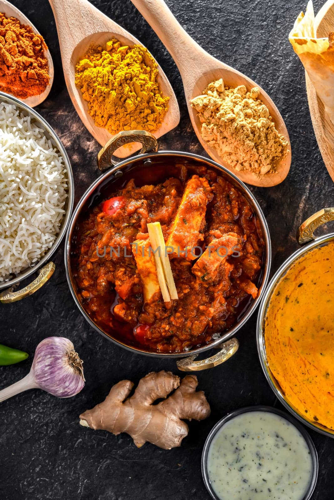 Composition with indian dishes: madras paneer, palak paneer and shahi paneer with basmati rice served in original indian karahi pots.