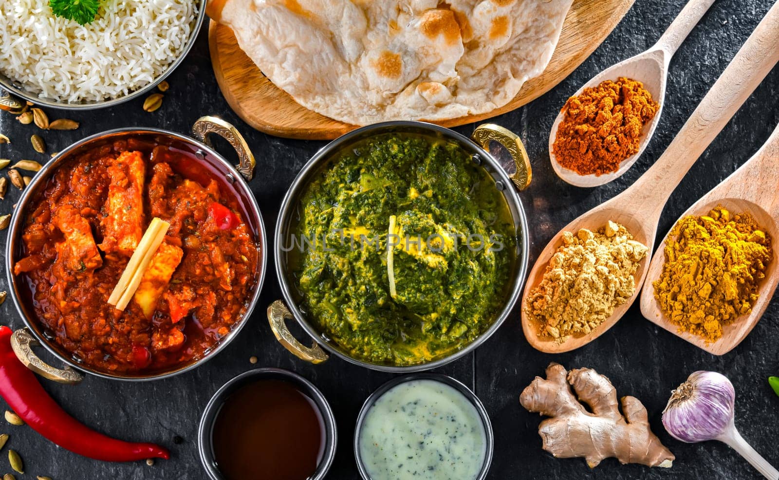 Composition with indian dishes: madras paneer, palak paneer and shahi paneer with basmati rice served in original indian karahi pots.