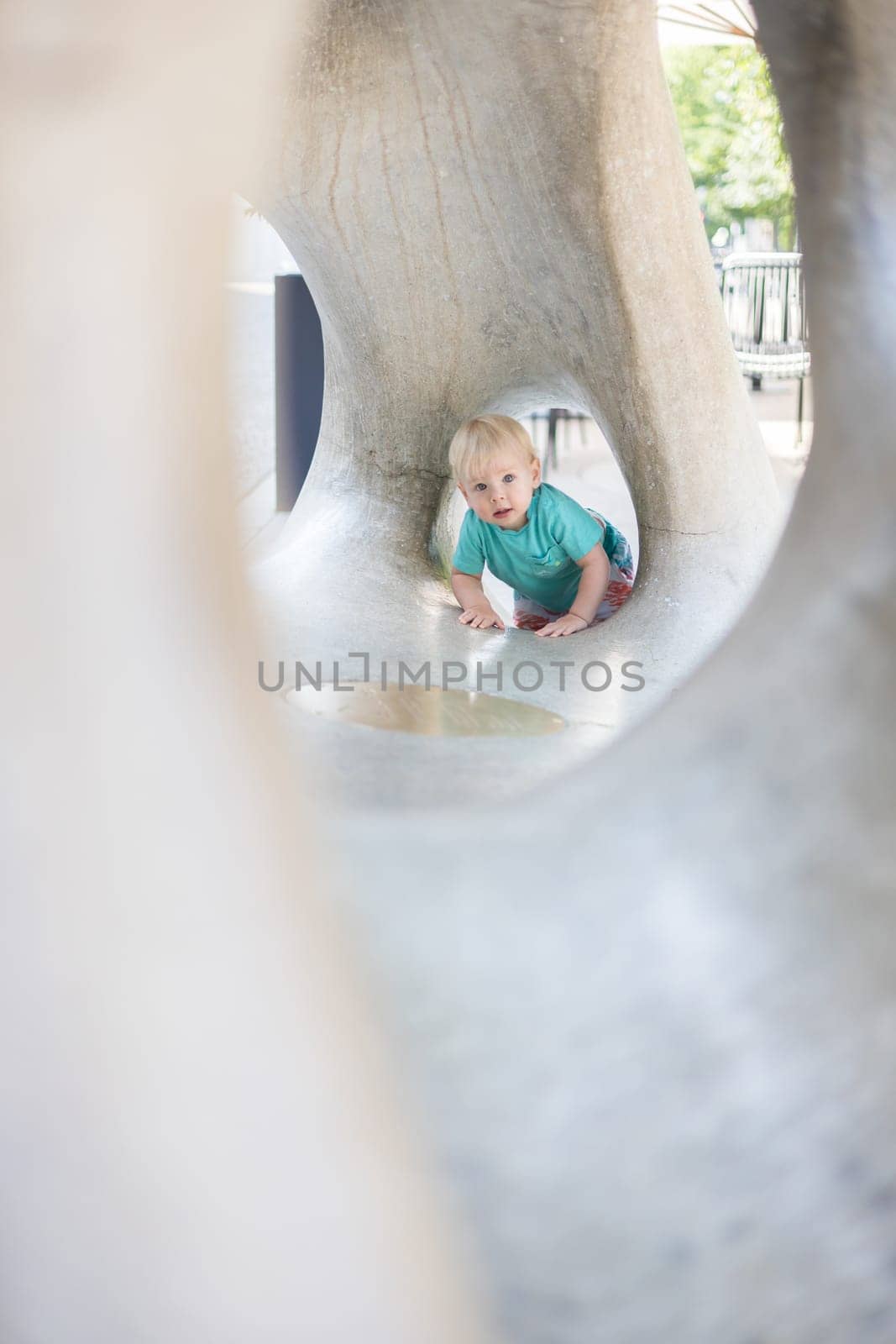 Child playing on outdoor playground. Toddler plays on school or kindergarten yard. Active kid on stone sculpured slide. Healthy summer activity for children. Little boy climbing outdoors