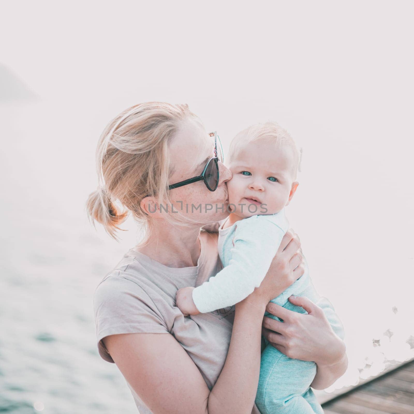Tender woman caressing her little baby boy infant child outdoors. Mother's unconditional love for her child.