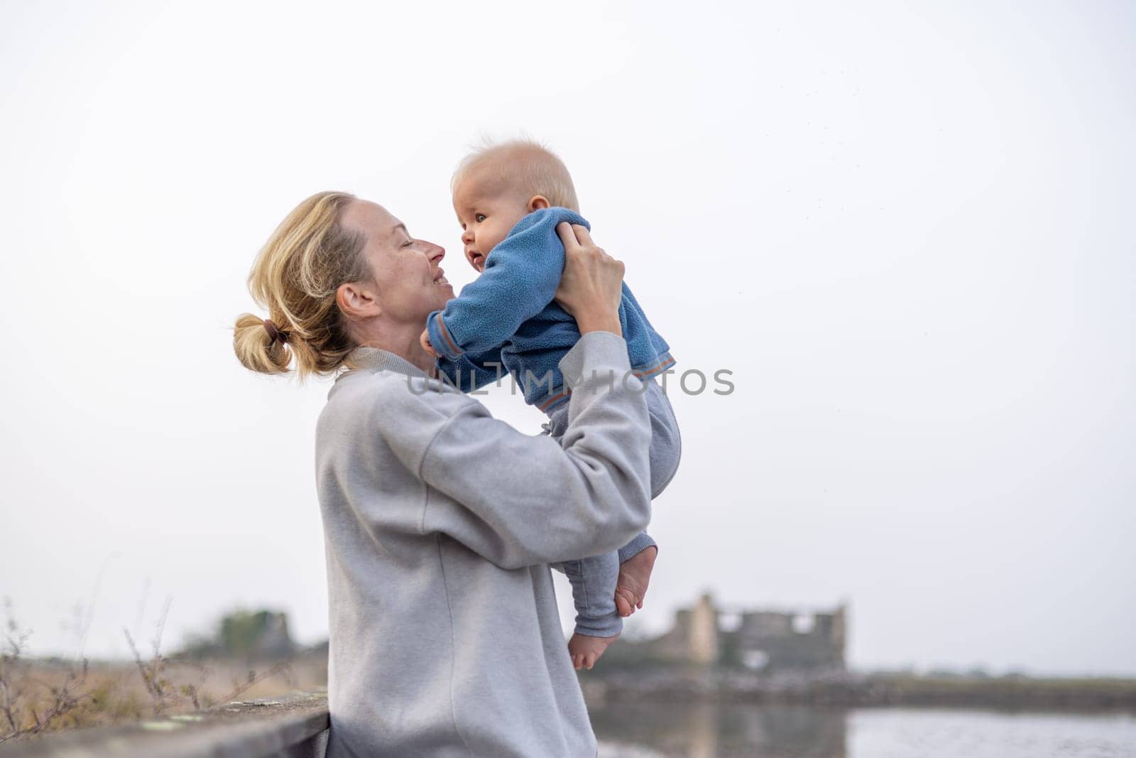 Tender woman caressing her little baby boy infant child outdoors on autumn trip to Secovlje salinas landscape park, Slovenia. Mother's unconditional love for her child