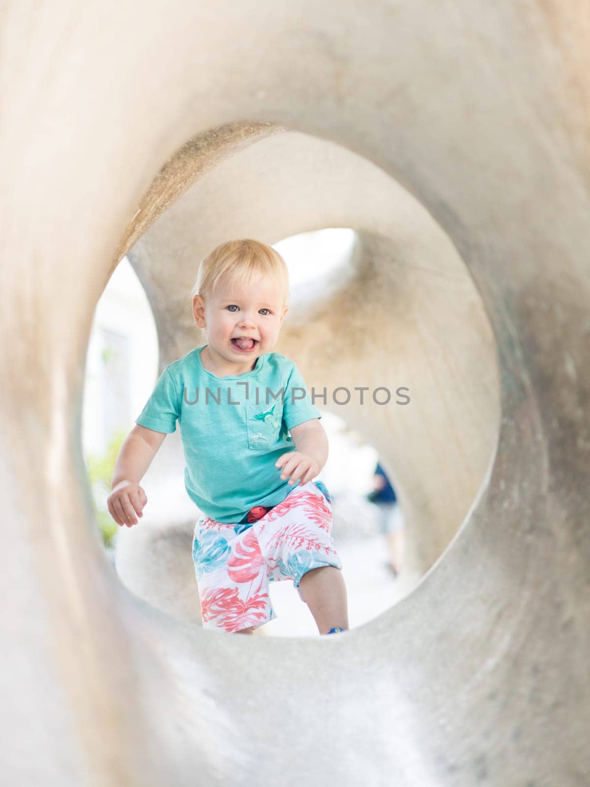 Child playing on outdoor playground. Toddler plays on school or kindergarten yard. Active kid on stone sculpured slide. Healthy summer activity for children. Little boy climbing outdoors