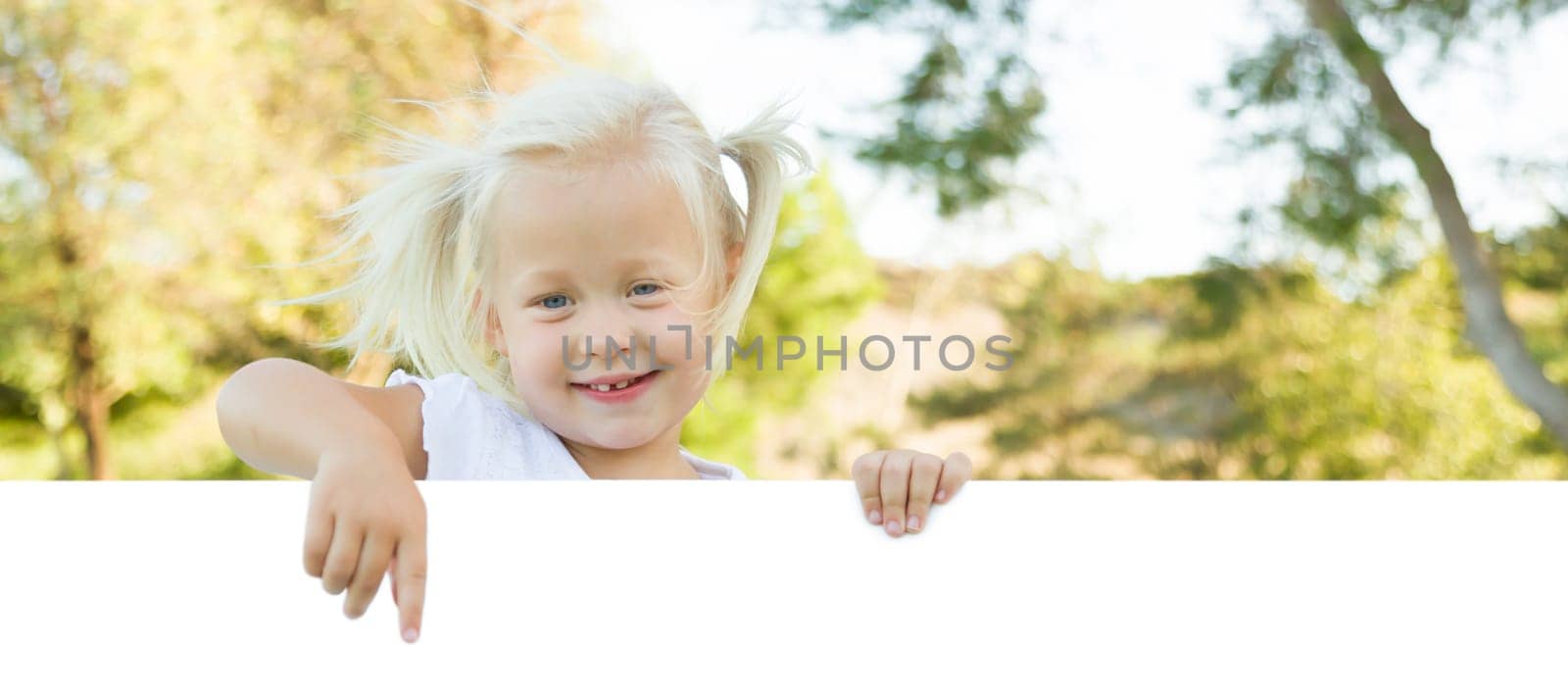 Cute Little Girl Outside Holding Edge of White Board with Room For Text.