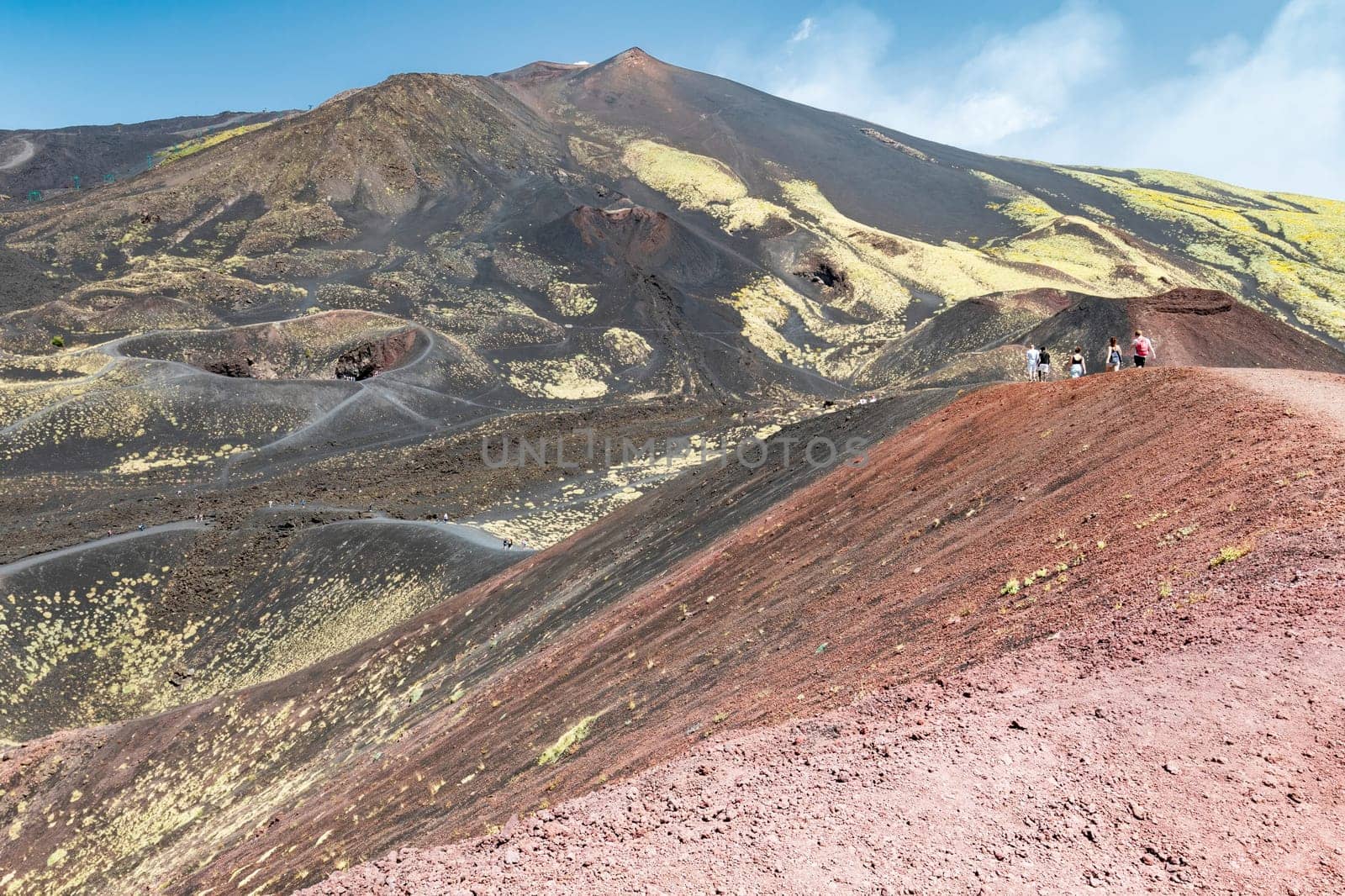 Tourists walking on the slopes of Mount Etna on the island of Sicily, Italy