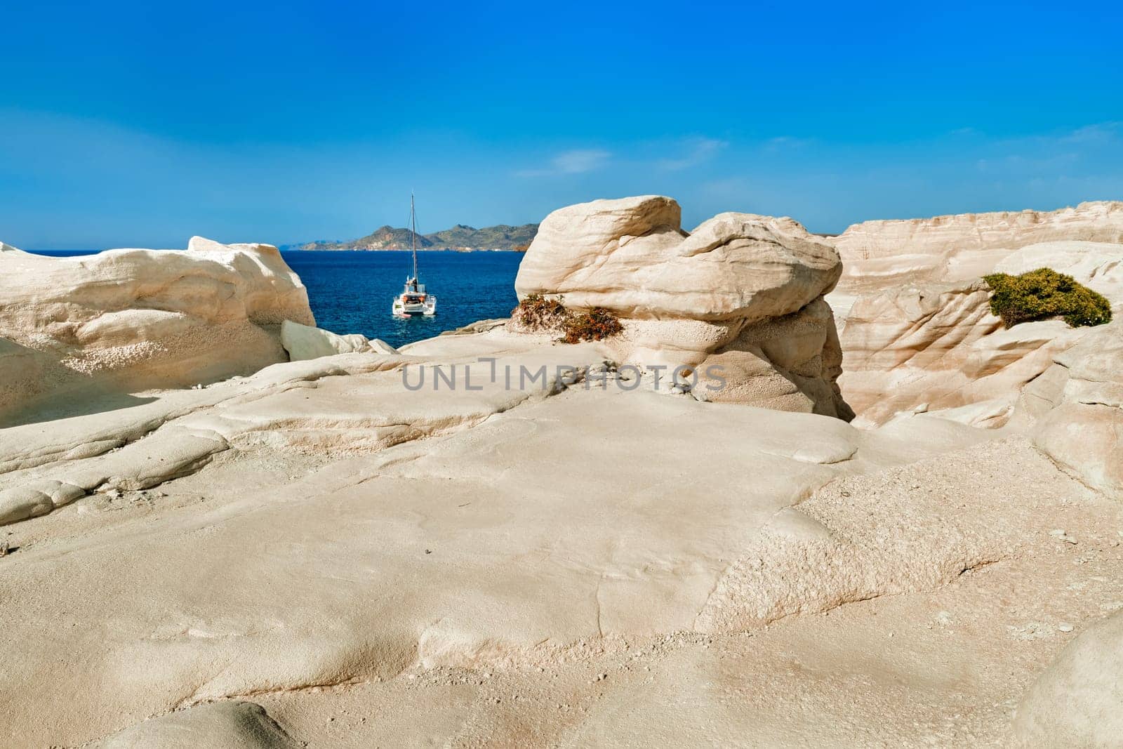 Famous white rocks of Sarakiniko beach, Aegean sea, Milos island , Greece. No people, lonely sailboat, empty cliffs, summer day sunshine, clear sea, blue waters, no clouds sky,beautiful landscape, fantastic rocks of tourist destination.