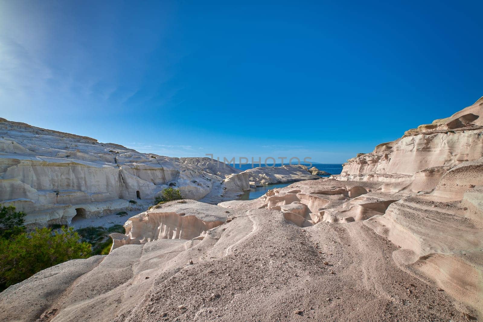 Famous white rocks of Sarakiniko beach, Aegean sea, Milos island , Greece. No people, empty cliffs, summer day sunshine, beautiful landscape, blue sky and clouds, fantastic gorge, tourist destination.
