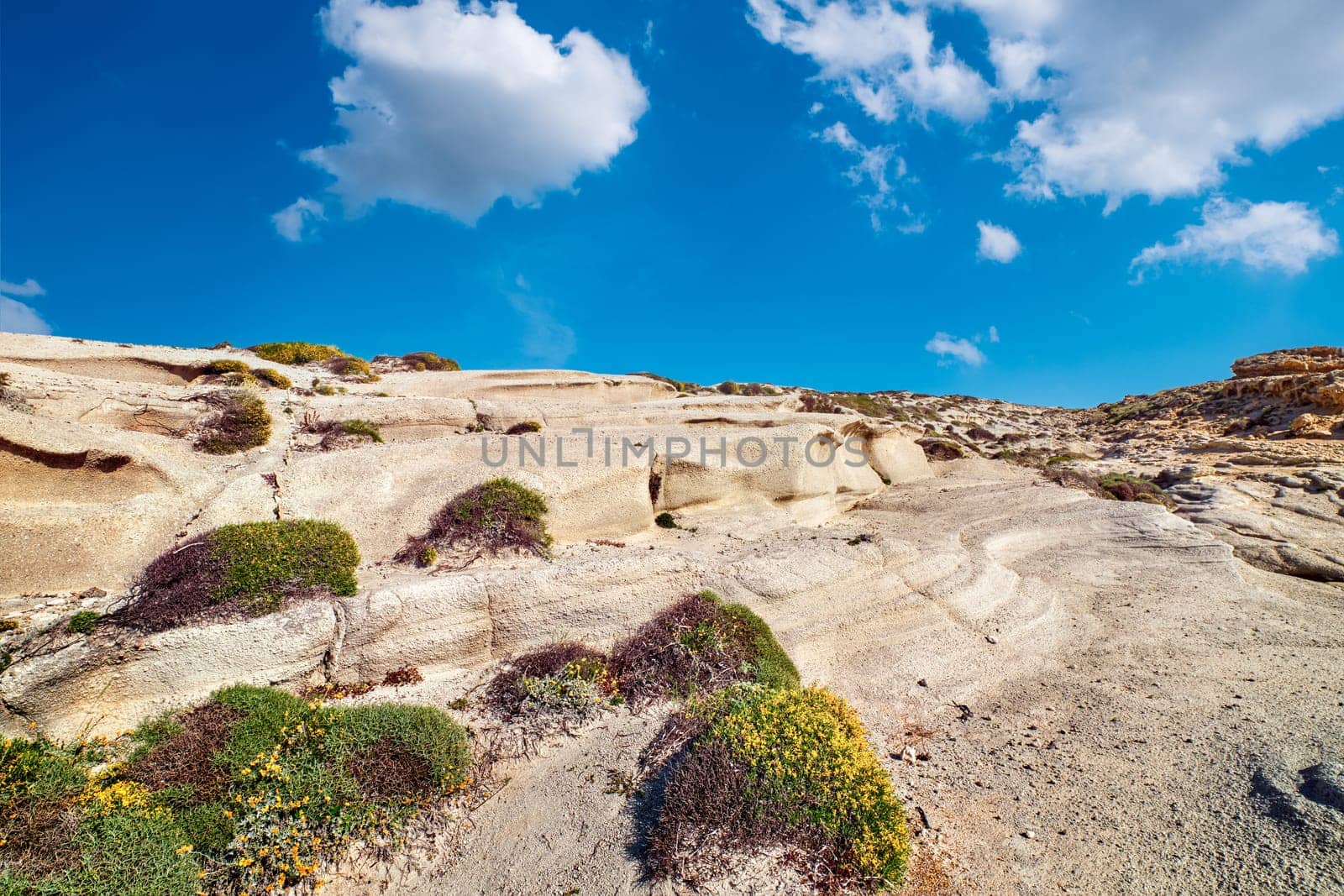 Summer landscape of white rocks on Sarakiniko beach, Aegean sea, Milos island , Greece. No people, empty cliffs, day, sunshine, beautiful blue sky and cloud, fantastic rocks of tourist destination.