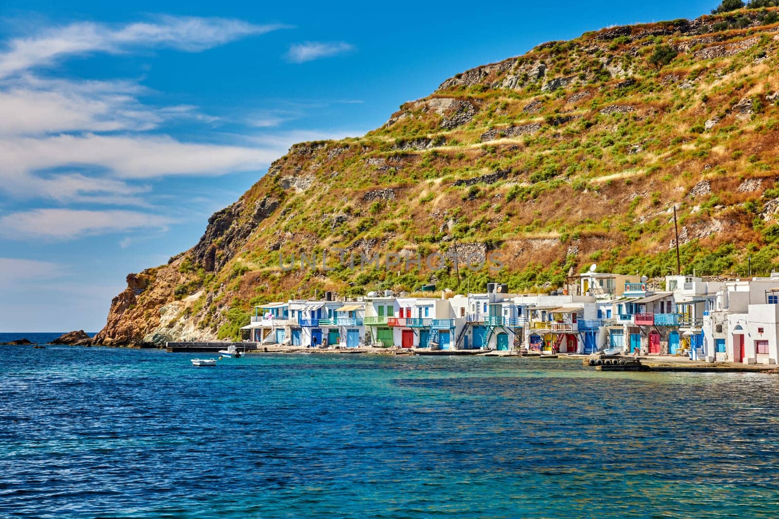 Colorful village of Klima with Greek whitewashed houses on sunny day, Milos island, Cyclades, Greece. Traditional fishermen village, bright painted and weathered doors and doorways, high hill, great blue sky, azure sea, summer sunshine, vacations.