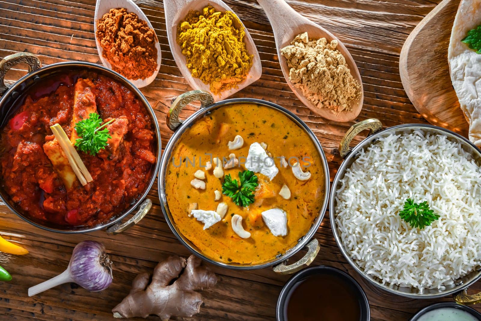Composition with indian dishes: madras paneer, palak paneer and shahi paneer with basmati rice served in original indian karahi pots.