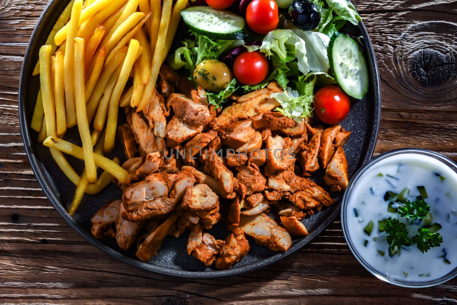 Kebab served with french fries, vegetable salad and tzatziki