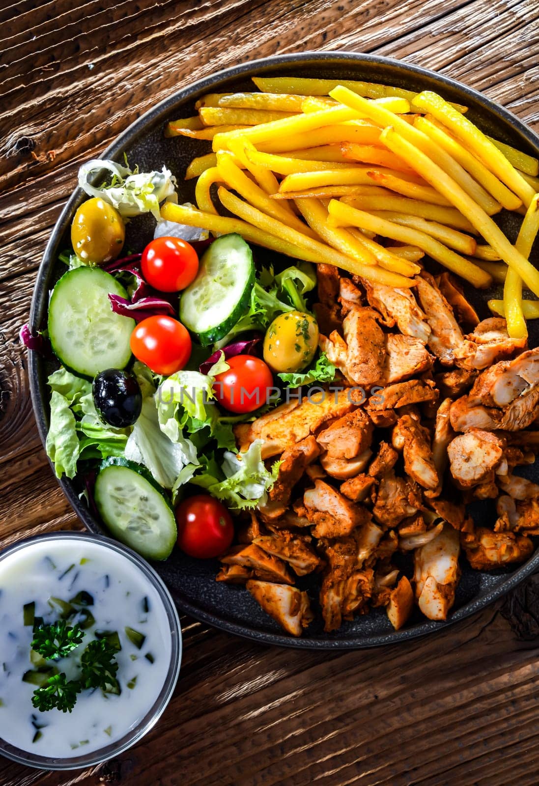 Kebab served with french fries, vegetable salad and tzatziki