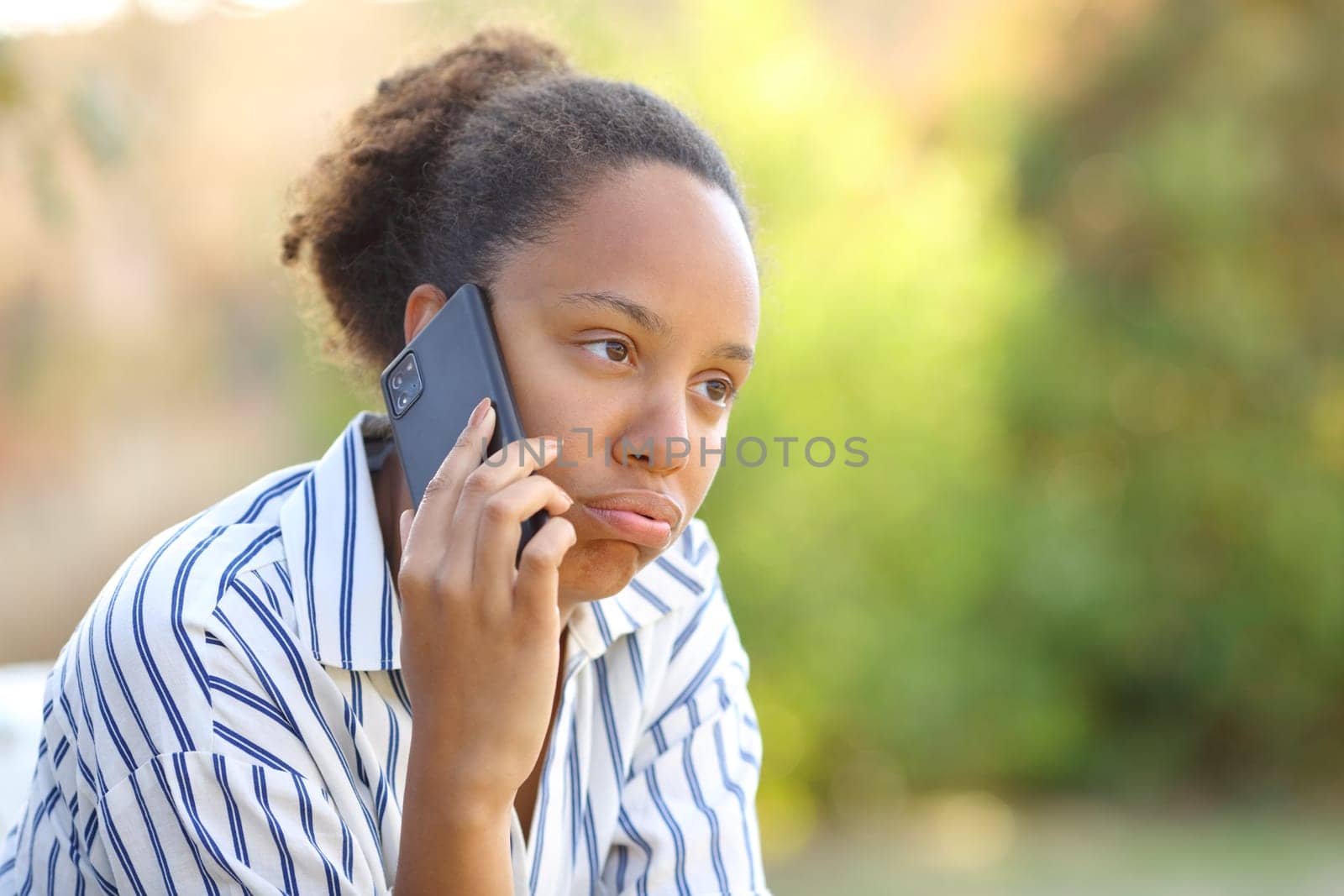 Impatient black woman complaining talking on phone in a park