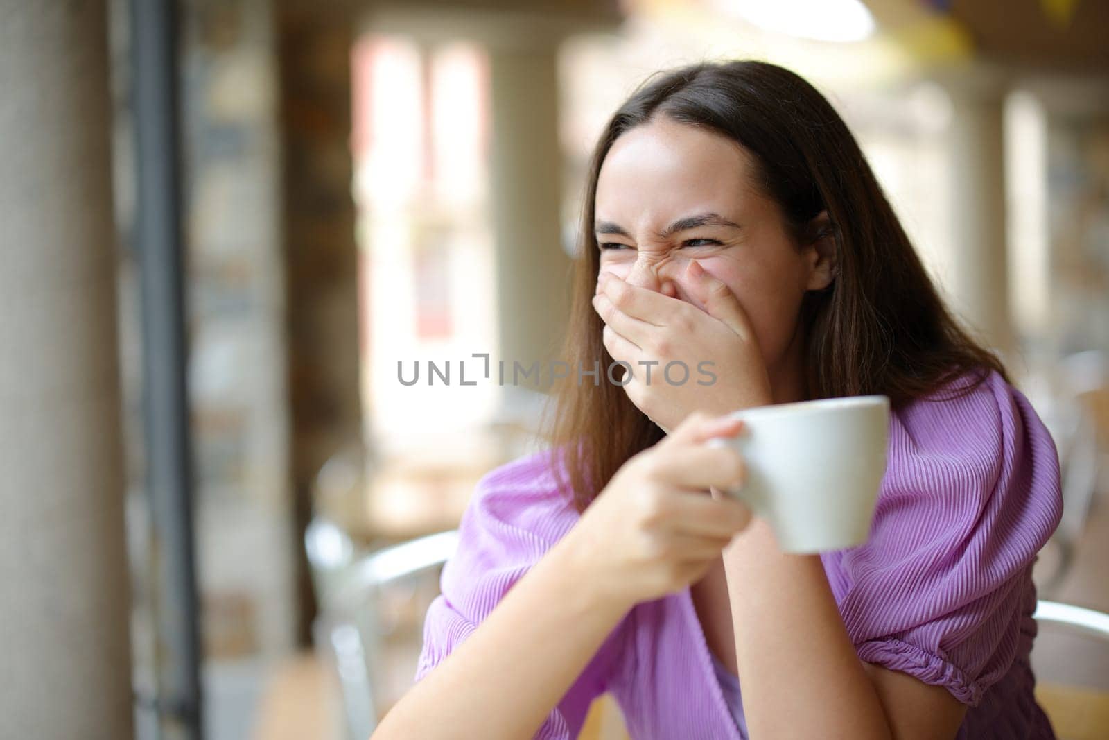 Happy woman drinking coffee laughing loud in a bar terrace