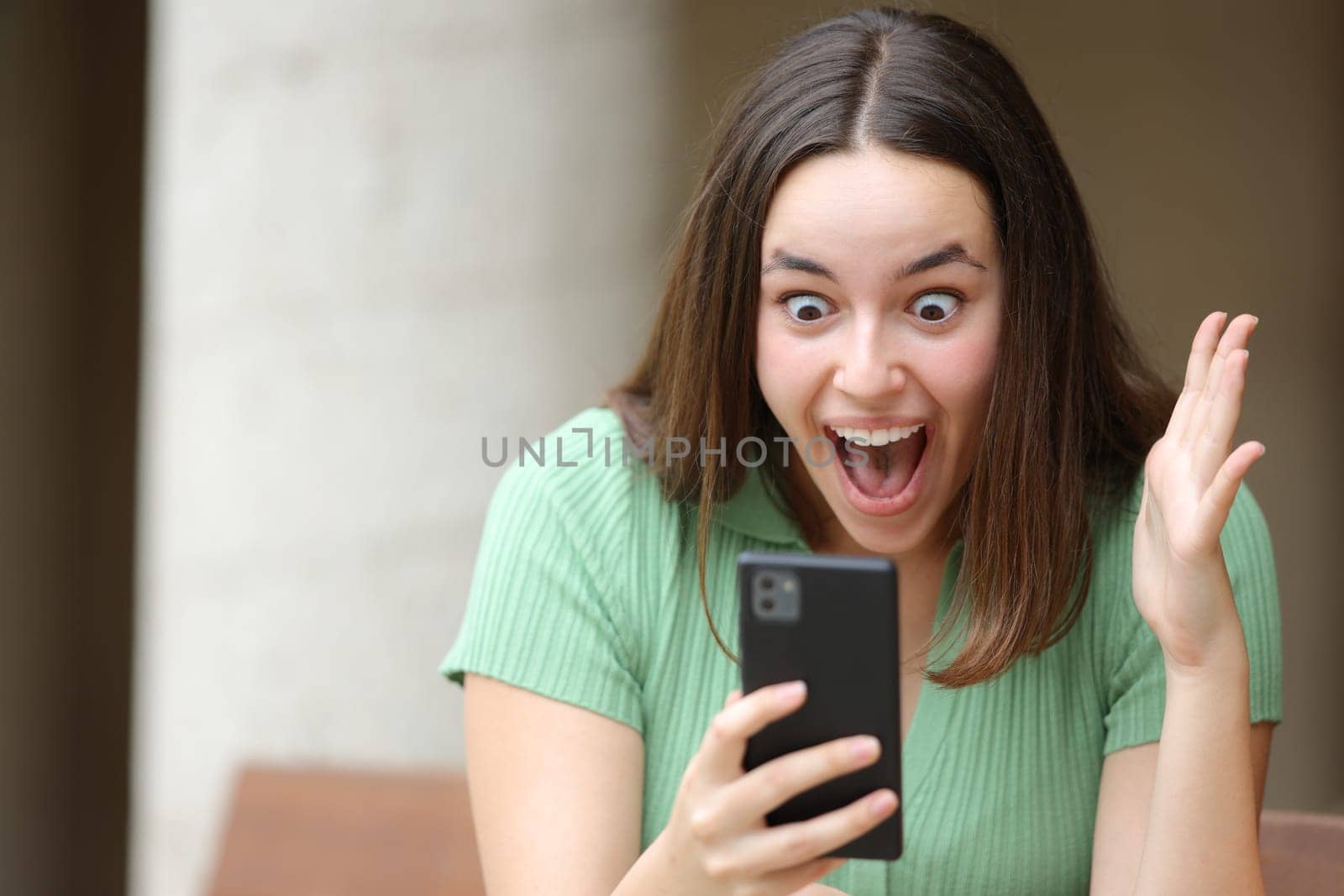 Excited woman checking amazing content on phone in the street