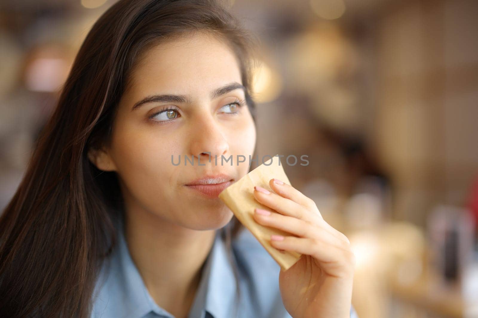 Restaurant customer cleaning mouth with paper tissue looking away